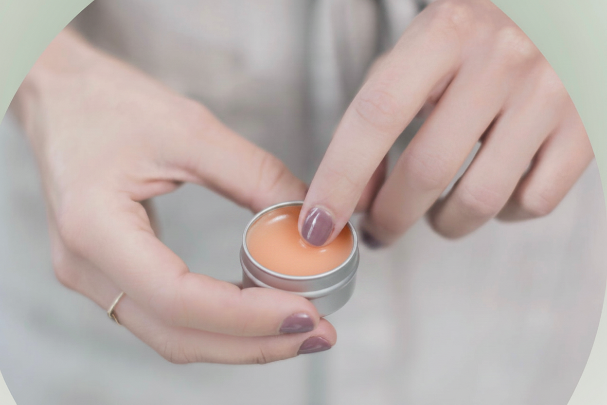 Rectangular image of finger in cream lip balm